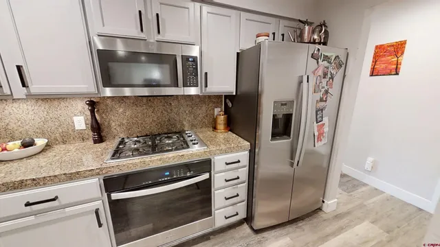 a kitchen with stainless steel appliances granite countertop a refrigerator stove and microwave