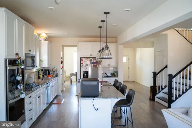 a large kitchen with sink a refrigerator a stove a dining table and chairs