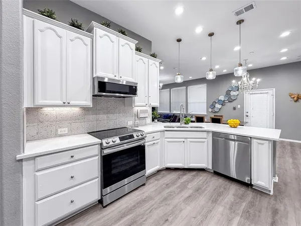 a kitchen with stainless steel appliances granite countertop a stove a sink and white cabinets