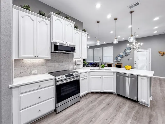 a kitchen with stainless steel appliances granite countertop a stove a sink and white cabinets