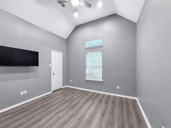 an empty room with wooden floor and windows