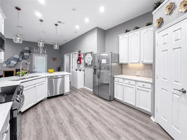 a kitchen that has a lot of white cabinets and stainless steel appliances