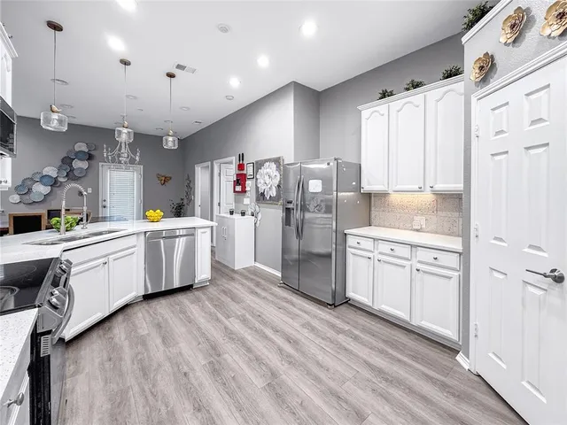 a kitchen that has a lot of white cabinets and stainless steel appliances