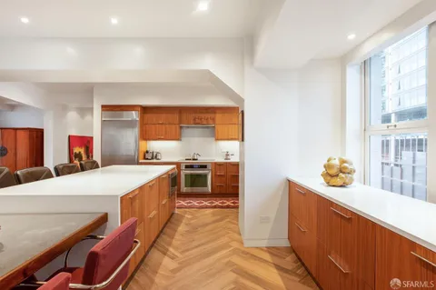 a large kitchen with stainless steel appliances wooden floor and a large window
