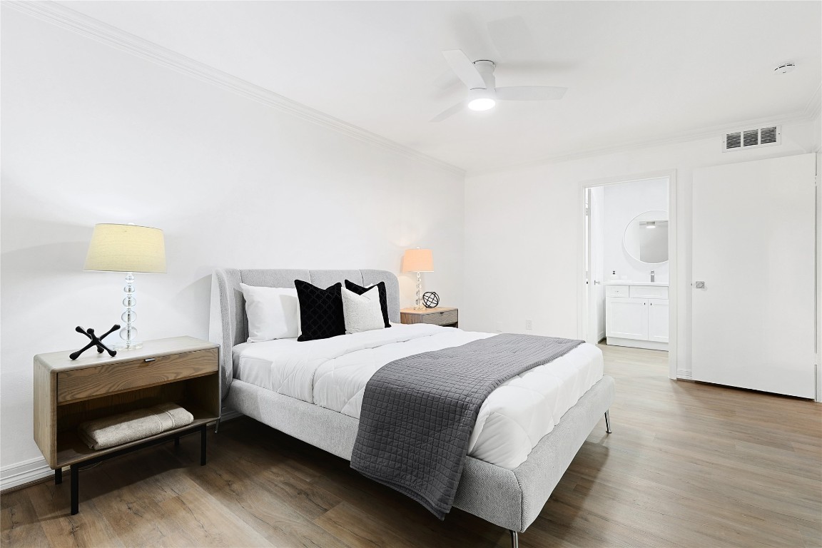 526 Colquitt Street Houston, TX 77006 - Photo 24 of 30 Another secondary bedroom featuring a modern design with a neutral color palette. It has a comfortable bed, stylish side tables, and ample lighting, complemented by hardwood flooring and a ceiling fan for comfort.