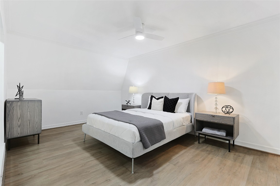 526 Colquitt Street Houston, TX 77006 - Photo 28 of 30 Another secondary bedroom featuring a modern design with a neutral color palette. It has a comfortable bed, stylish side tables, and ample lighting, complemented by hardwood flooring and a ceiling fan for comfort.