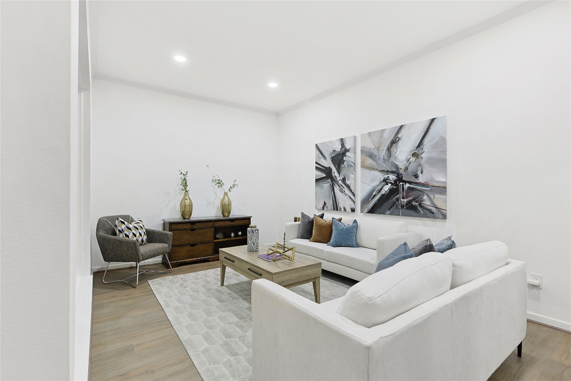 526 Colquitt Street Houston, TX 77006 - Photo 5 of 30 The inviting living room features a modern design with neutral tones, a comfortable white sofa, stylish armchair, and a wooden coffee table. Contemporary artwork and decorative pieces add a touch of elegance. The room is well-lit with recessed lighting and has a warm, welcoming atmosphere.