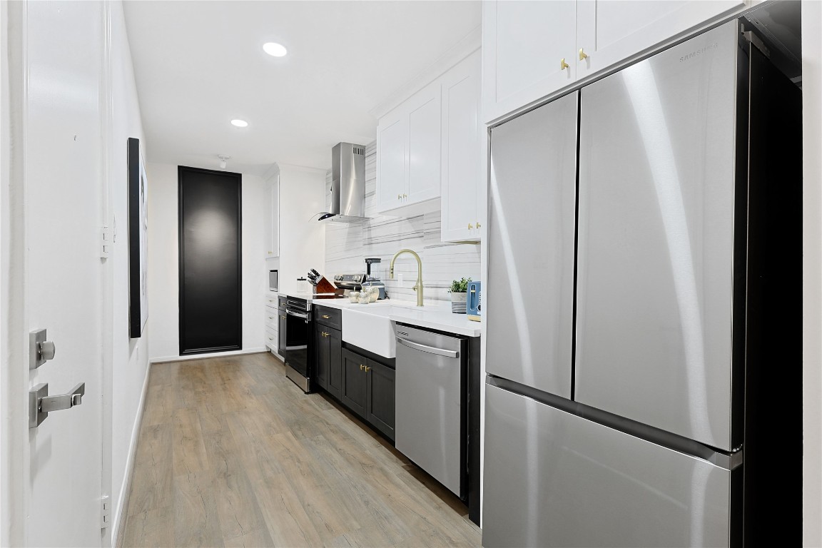 526 Colquitt Street Houston, TX 77006 - Photo 10 of 30 The stylish kitchen features sleek stainless steel appliances, white and black cabinetry, and light wood flooring. Ample counter space and a chalkboard wall enhance functionality and aesthetics.