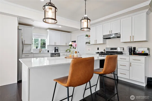 a kitchen with stainless steel appliances granite countertop a sink a stove a refrigerator cabinets and chairs