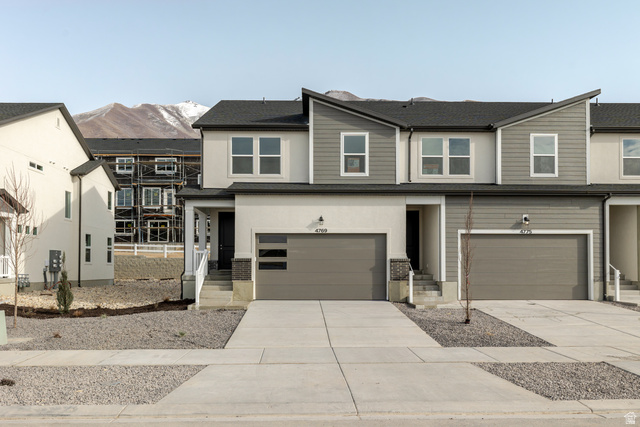 View of front facade featuring driveway, a garage, a mountain view, and stucco siding