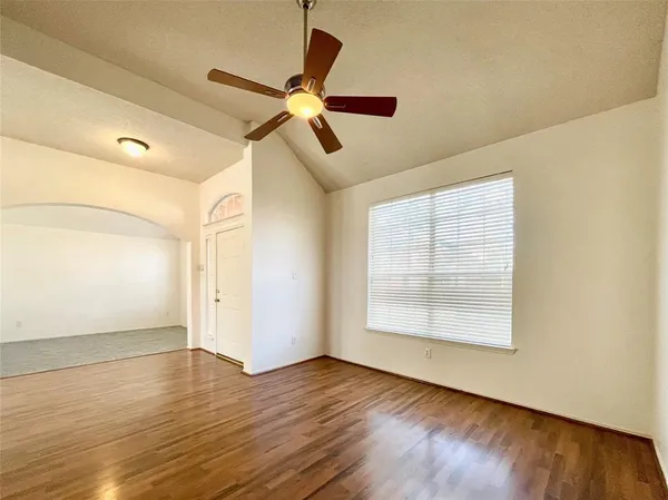 an empty room with wooden floor fan and windows