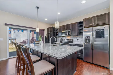 a kitchen with stainless steel appliances granite countertop a kitchen island a stove a table and chairs