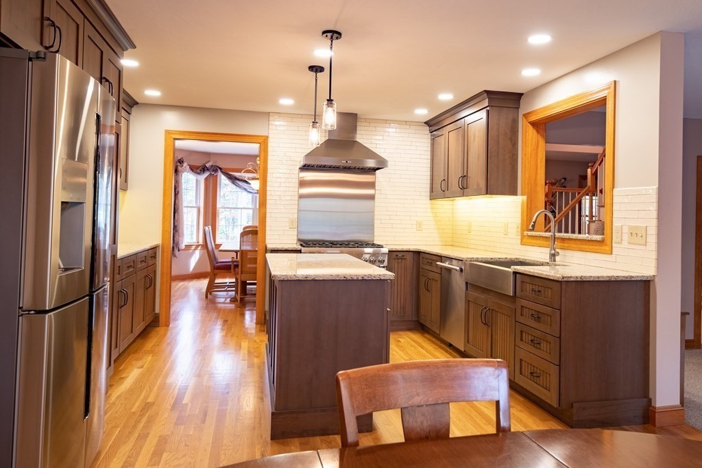 48 Easter Brook Road Lunenburg, MA 01462 - Photo 17 of 38 a kitchen with stainless steel appliances granite countertop a refrigerator a sink dishwasher a stove and a dining table with wooden floor