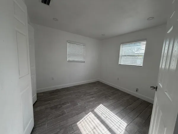 an empty room with wooden floor and windows
