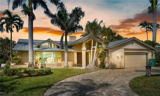 front view of house with a yard and palm trees