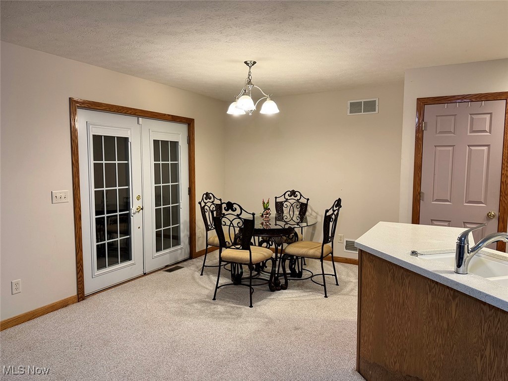 3718 Babcock Road Williamsfield, OH 44093 - Photo 21 of 31 Carpeted dining space with french doors, sink, a textured ceiling, and a notable chandelier