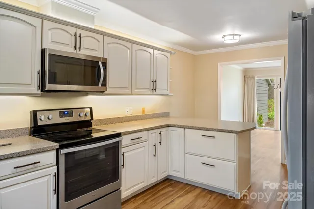a kitchen with cabinets stainless steel appliances and wooden floor