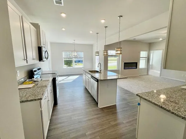 a large kitchen with granite countertop a large counter top stainless steel appliances and cabinets