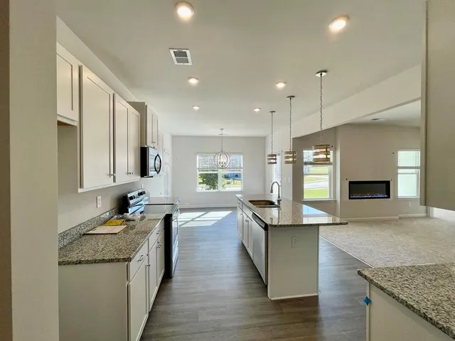 a large kitchen with granite countertop a large counter top a sink stainless steel appliances and cabinets