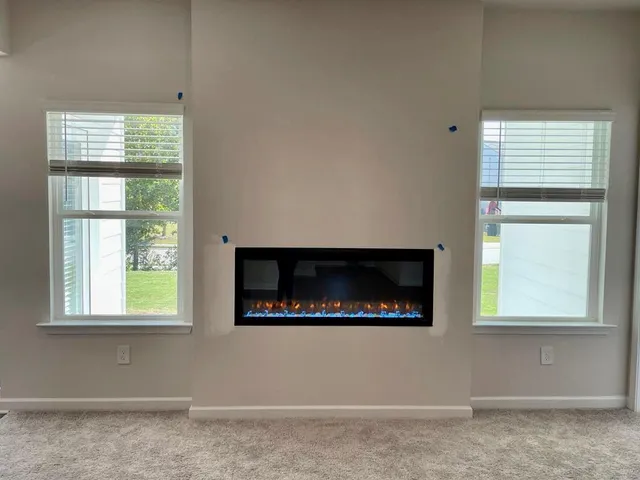 an empty room with windows and fireplace