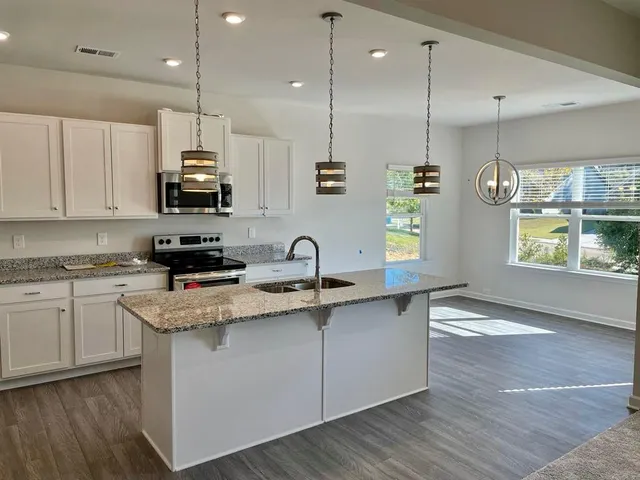 a kitchen with stainless steel appliances granite countertop a sink a stove and a wooden floors