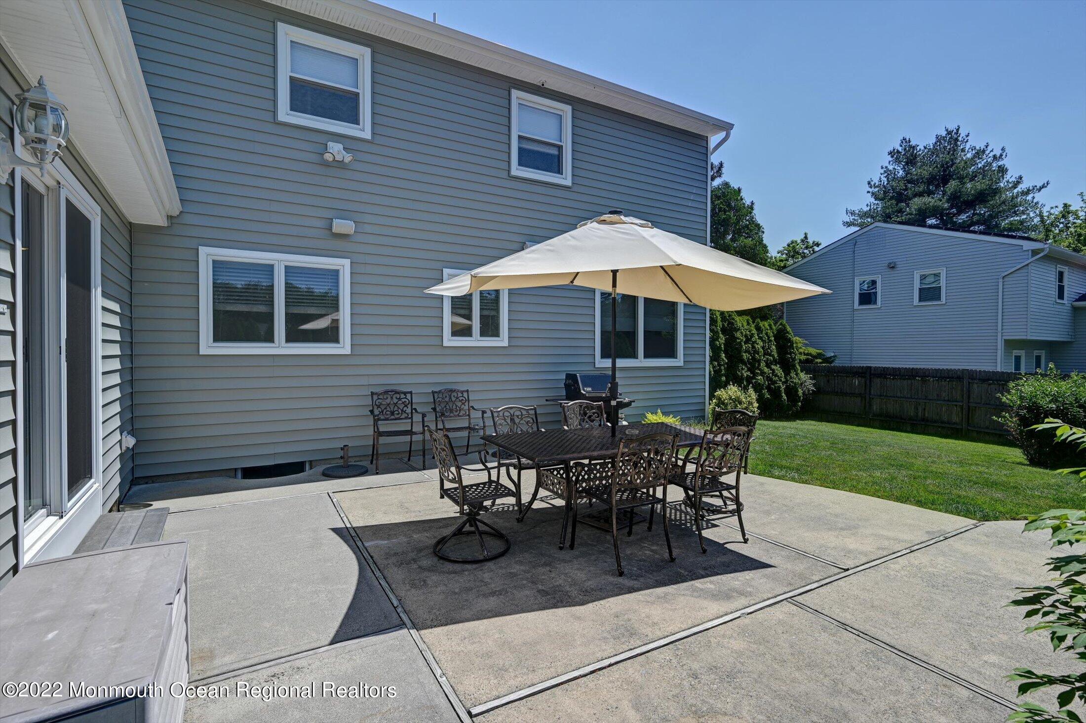 4 Sussex Road Morganville, NJ 07751 - Photo 32 of 55 a patio with a table and chairs under an umbrella