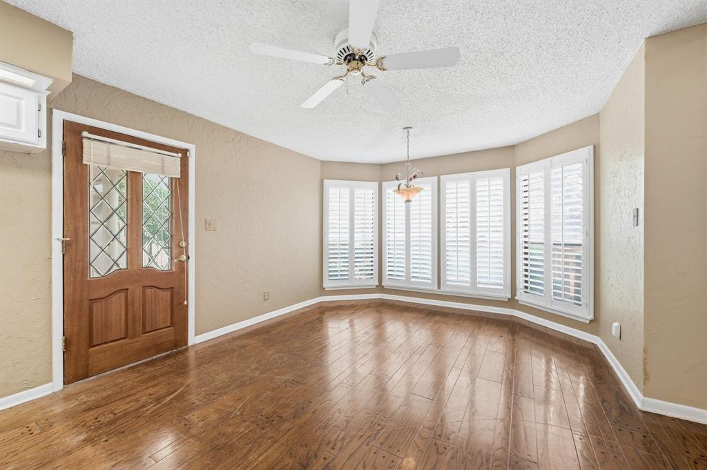 7260 Hudson Cemetery Road Mansfield, TX 76063 - Photo 11 of 40 Spacious room featuring wood-finish flooring, a decorative wood entry door with leaded glass, and a bay window with plantation shutters