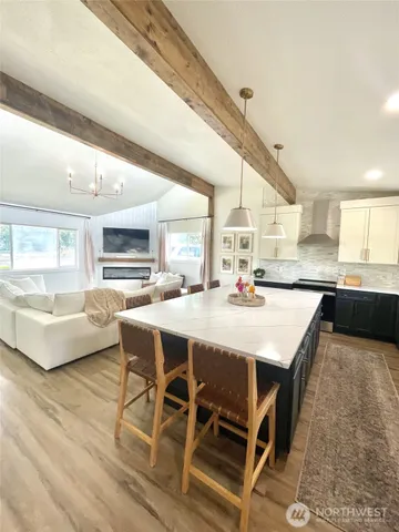 a kitchen with stainless steel appliances kitchen island granite countertop a table chairs sink and cabinets