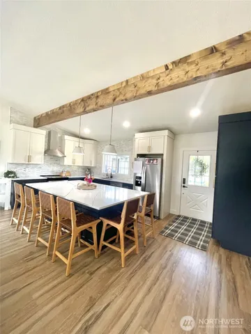 a dining hall with stainless steel appliances kitchen island granite countertop a table chairs and a refrigerator