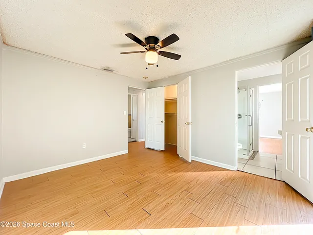 a view of empty room with wooden floor and ceiling fan