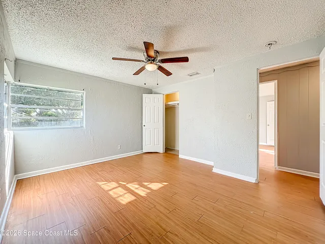 a view of empty room with wooden floor and fan