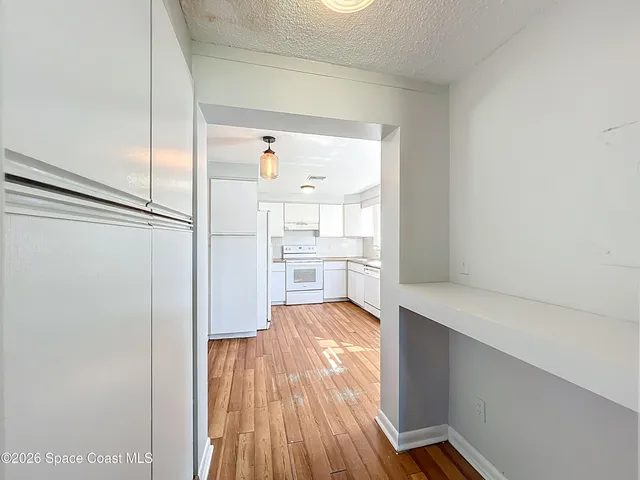 a view of a kitchen with wooden floor and a refrigerator
