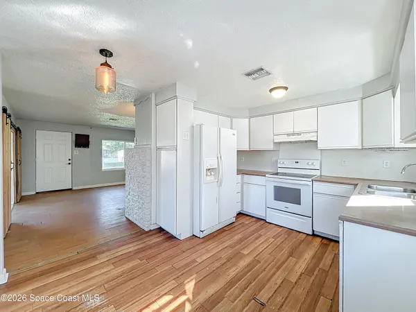 a kitchen with a refrigerator a stove top oven a counter space and wooden floor