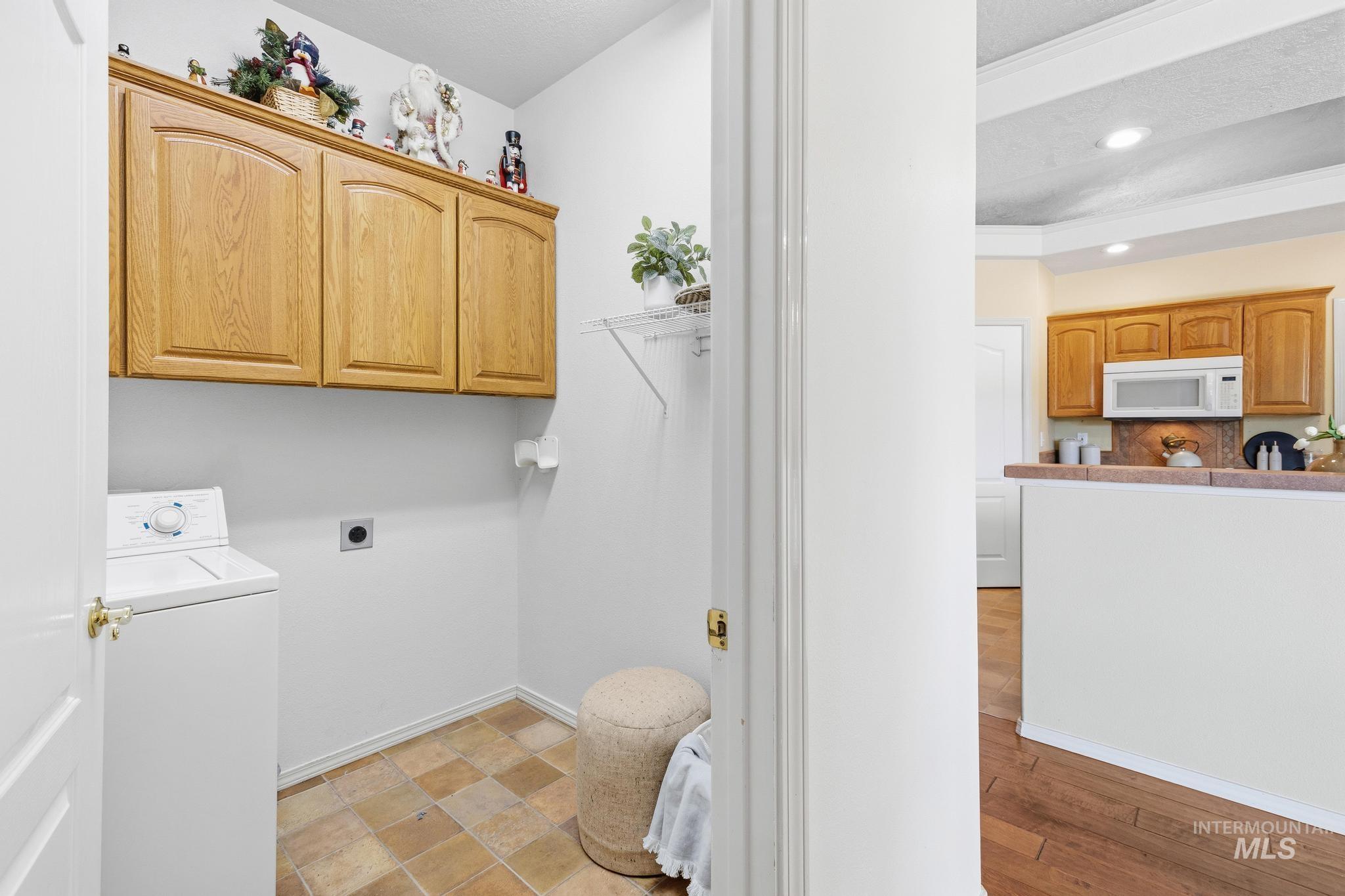15181 Drury Way Caldwell, ID 83607 - Photo 26 of 49 Dedicated utility area featuring warm wood cabinetry, a utility hookup, and neutral tile flooring