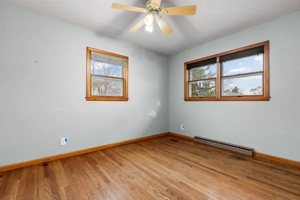 a view of empty room with wooden floor and fan