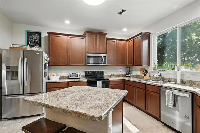 a kitchen with stainless steel appliances granite countertop refrigerator sink and stove