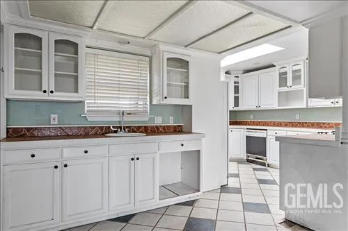 a kitchen with granite countertop a stove a sink and white cabinets
