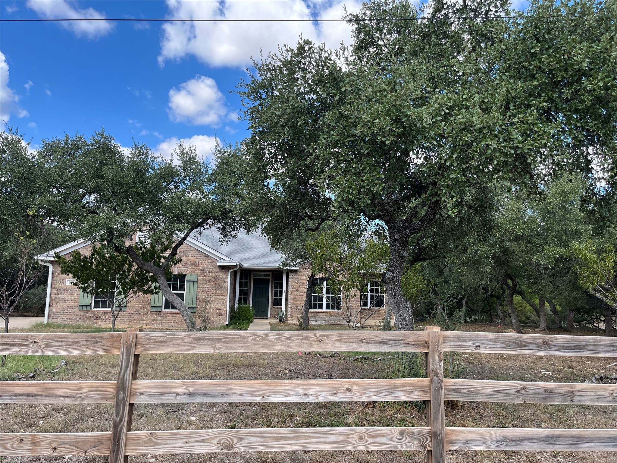 205 Homestead Road Kyle, TX 78640 - Photo 2 of 28 Mature trees frame this traditional brick home, offering natural shade and a sense of privacy.