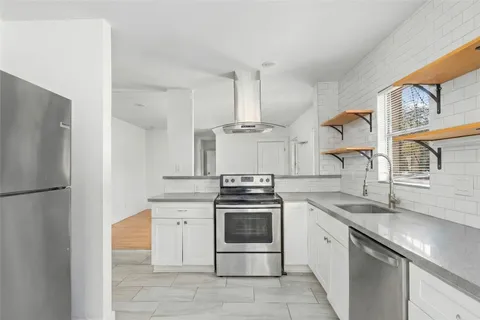 a kitchen with stainless steel appliances granite countertop a sink a stove a refrigerator and a granite counter tops with white cabinets