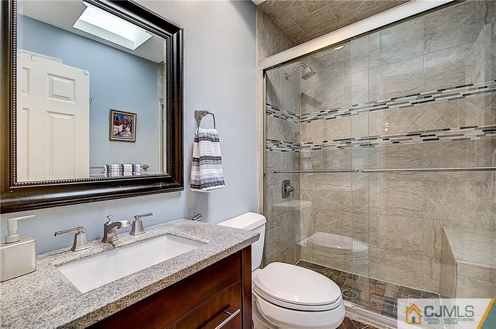 4505 Stonehedge Road Edison, NJ 08820 - Photo 18 of 25 a bathroom with a granite countertop sink toilet a mirror and shower