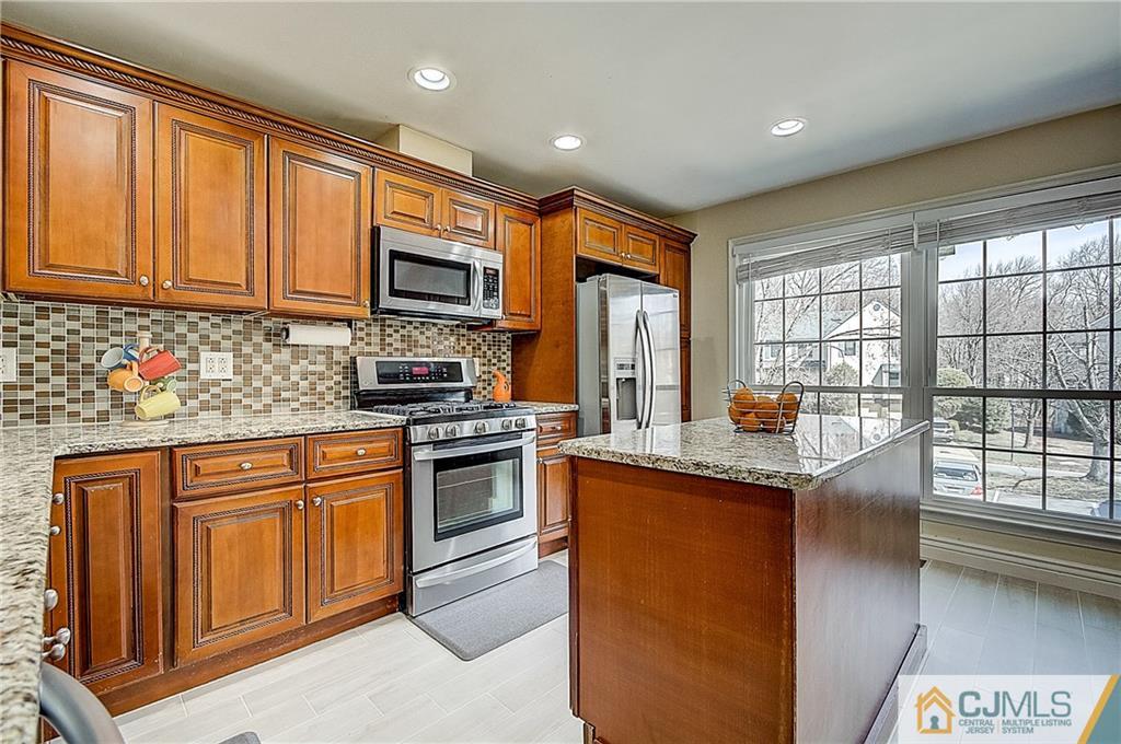 4505 Stonehedge Road Edison, NJ 08820 - Photo 8 of 25 a kitchen with stainless steel appliances granite countertop a stove top oven a sink dishwasher a dining table and chairs with wooden floor