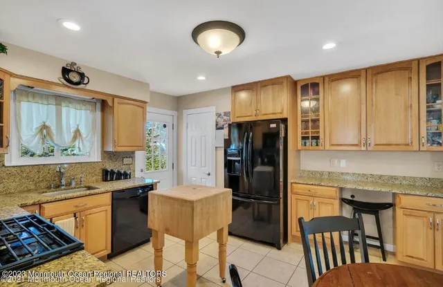 a kitchen with stainless steel appliances granite countertop a refrigerator a sink a stove and white cabinets with wooden floor