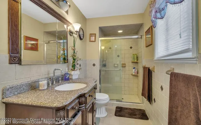 a bathroom with a granite countertop sink a toilet a mirror and shower