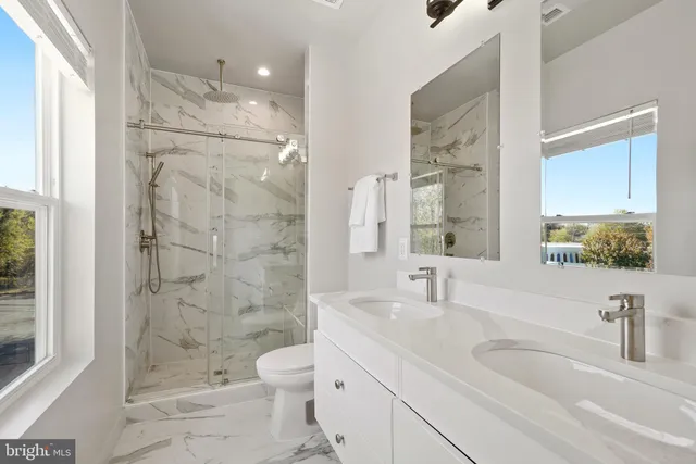 a bathroom with a granite countertop sink a toilet and shower