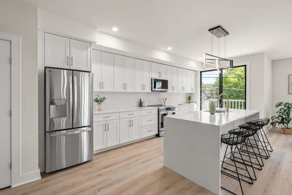 a kitchen with stainless steel appliances a refrigerator sink and wooden floor