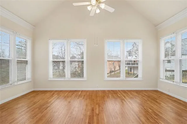 a view of an empty room with a window and wooden floor