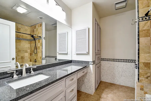 a bathroom with a granite countertop sink mirror and a bathtub