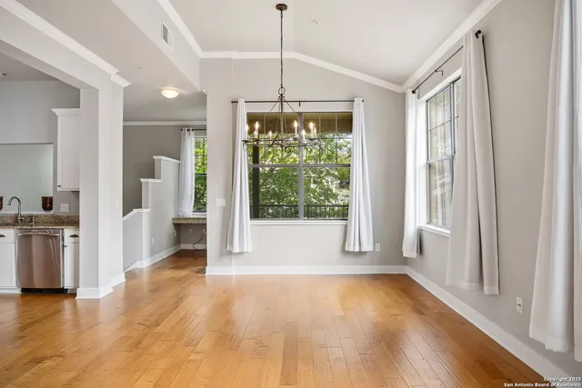 a view of a hallway with wooden floor and a kitchen