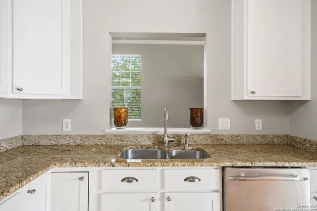 a kitchen with granite countertop white cabinets and a sink