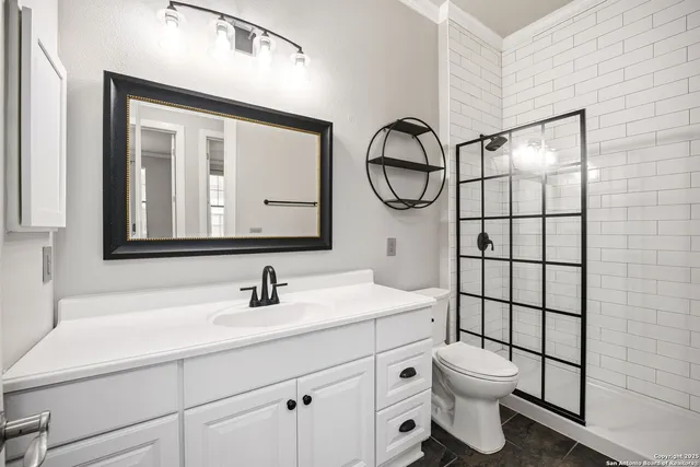 a bathroom with a toilet sink vanity and mirror
